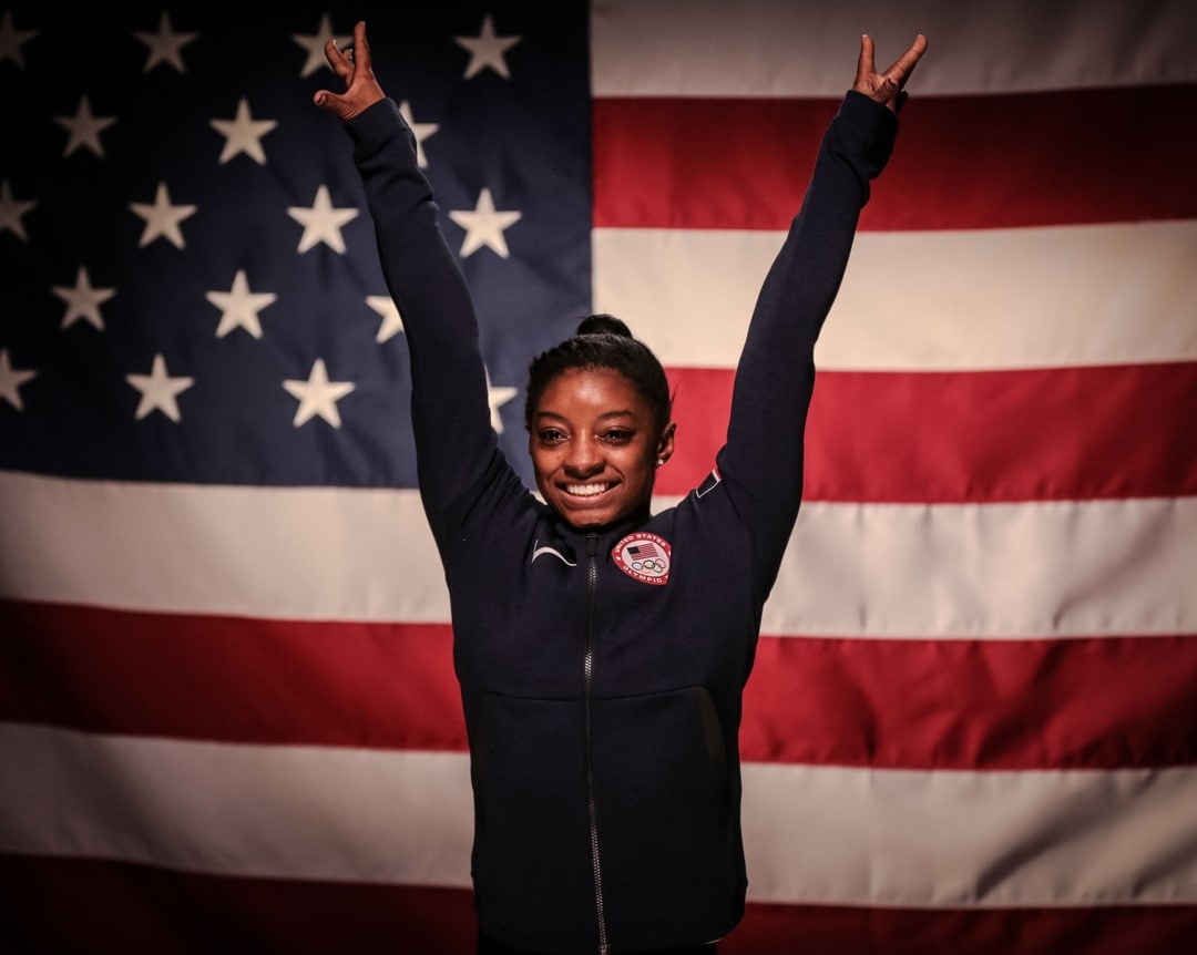 Simone Biles in front of US flag.